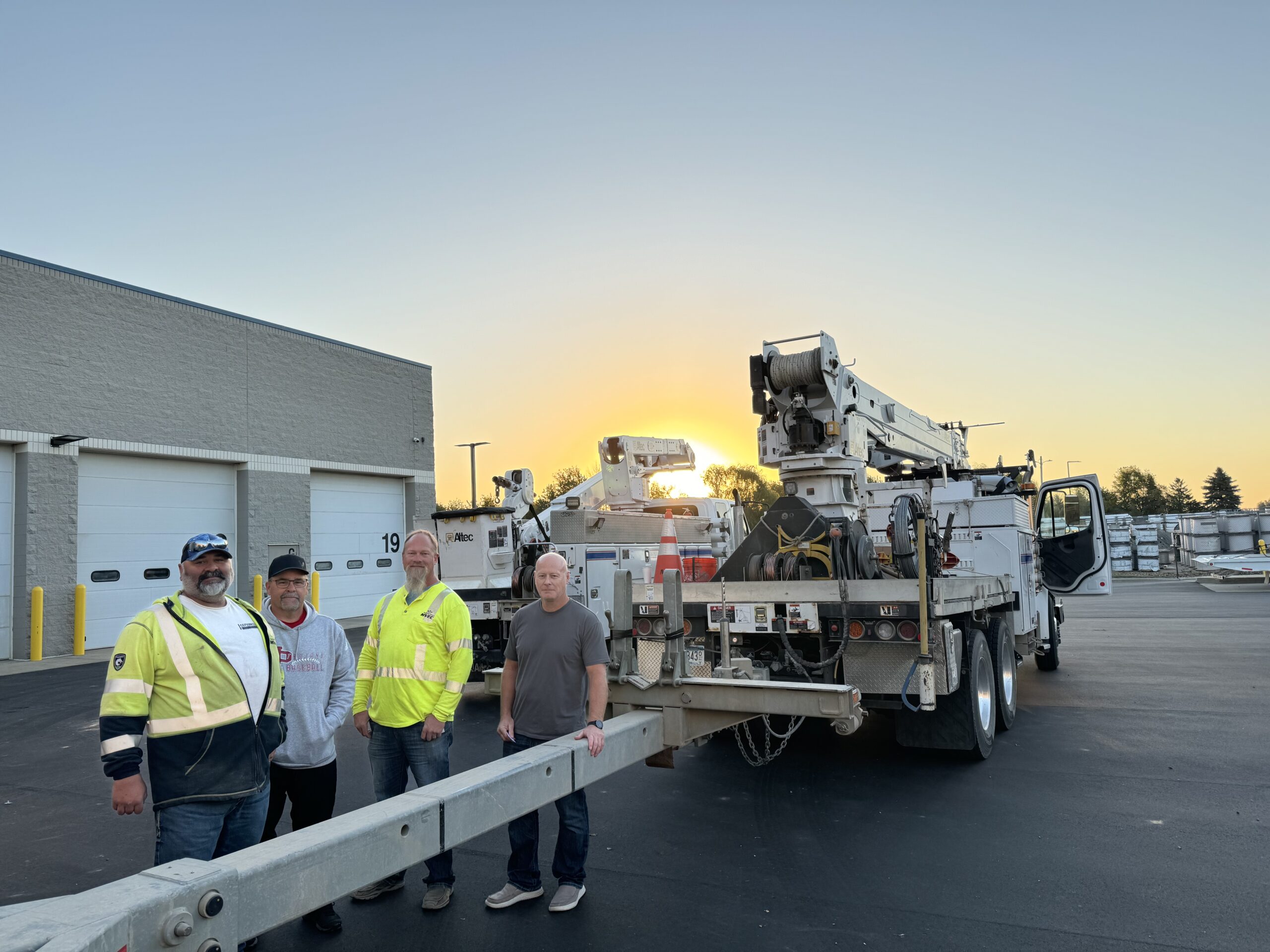 Four linemen with bucket truck and pole trailer.